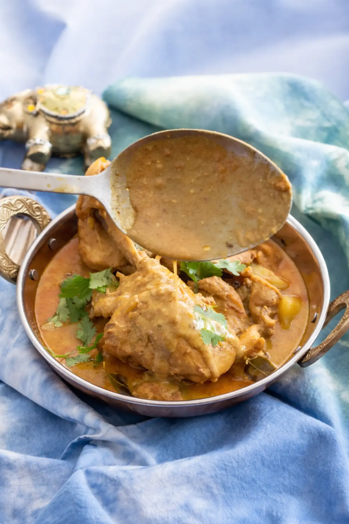 Spoon lifting creamy curry sauce over chicken.