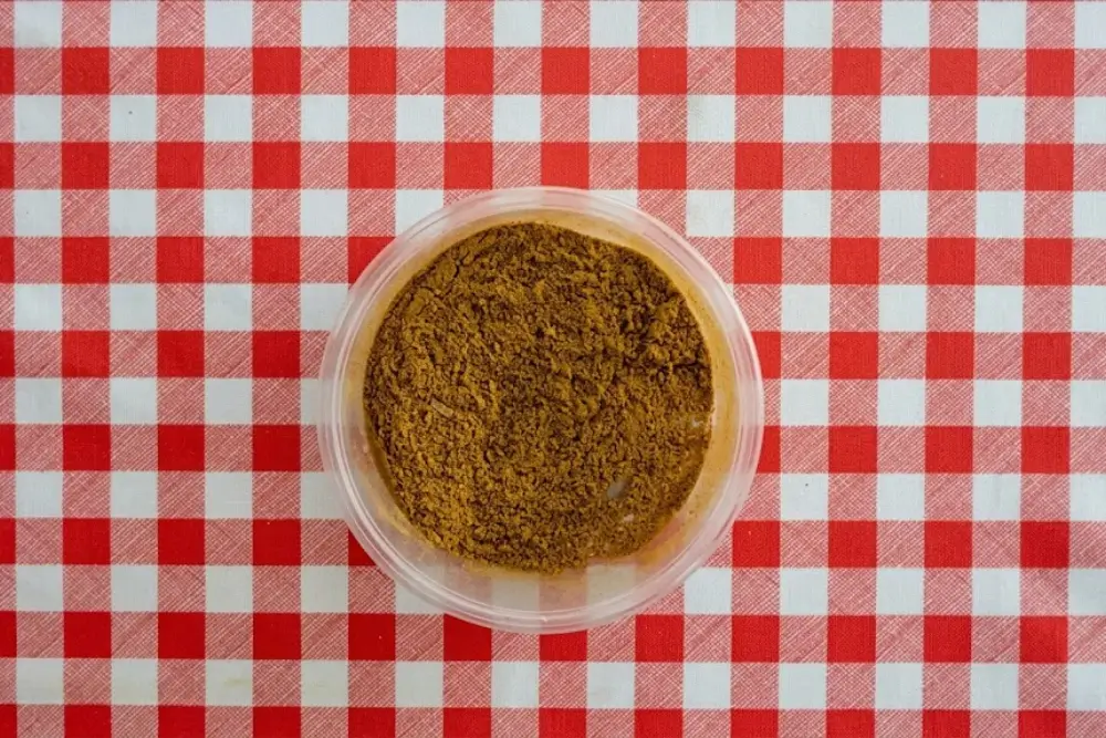 Fully combined curry seasoning in a round plastic container.