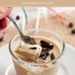 Spoon dipping into coffee panna cotta topped with chopped chocolate.