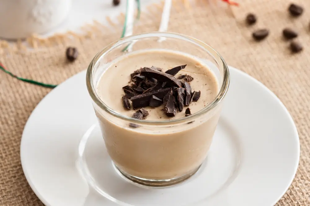 Coffee Panna Cotta served in a glass with chopped chocolate on top.