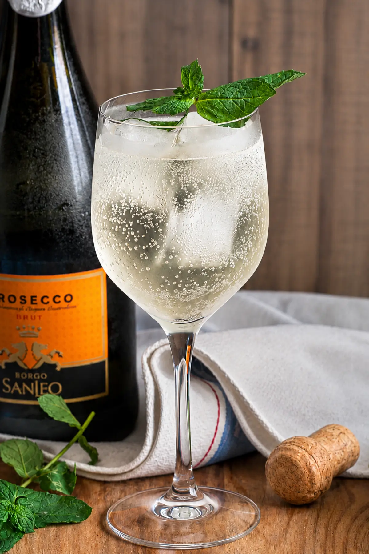 Hugo cocktail served with mint leaves, ice cubes, and chilled Prosecco in a wine glass.