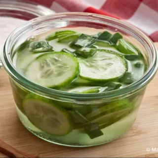 A jar filled with pickled cucumbers and green onions.
