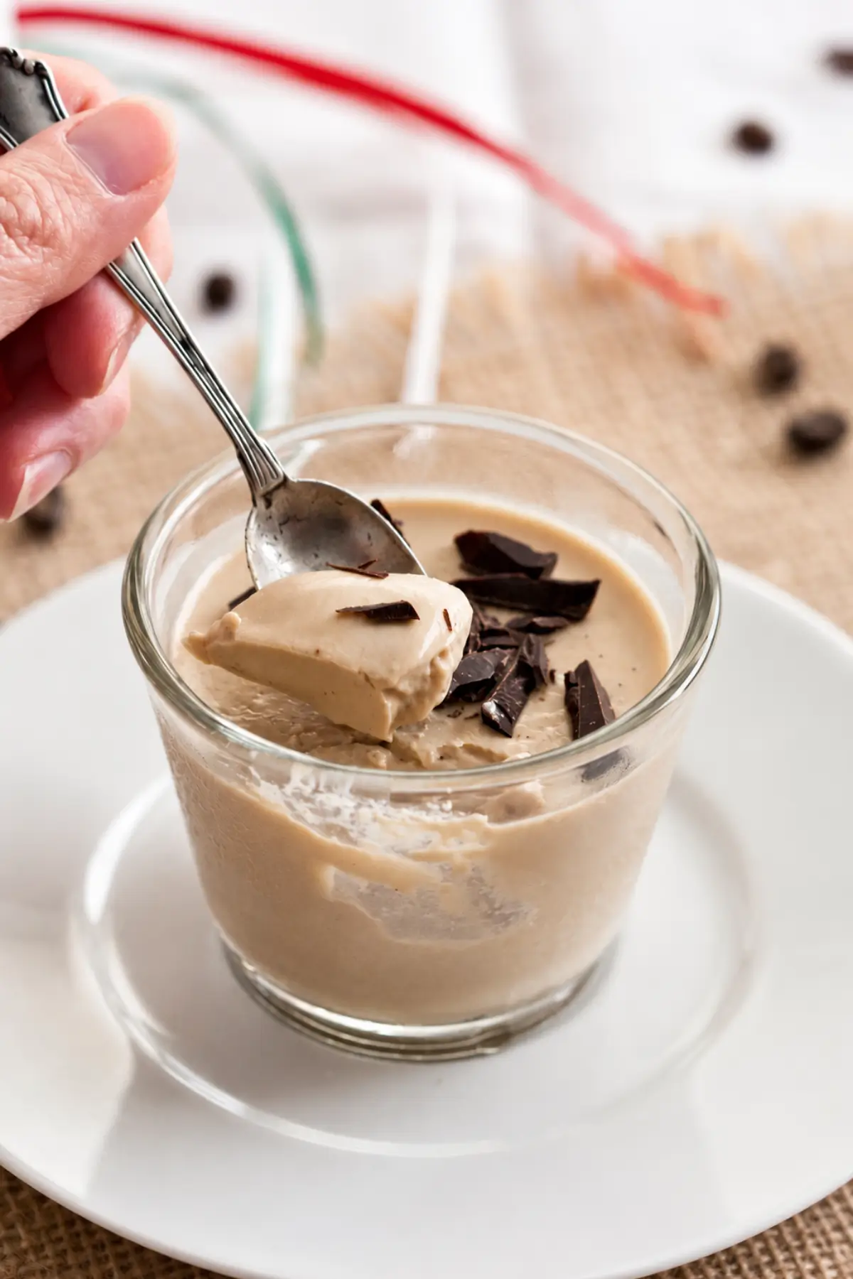 Spoonful of creamy coffee dessert with chocolate pieces on top.