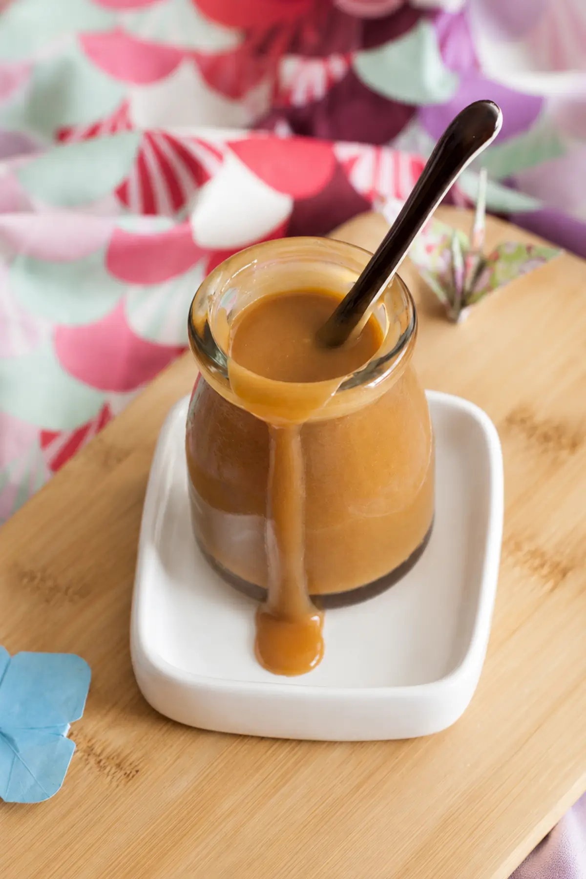 Miso Caramel Sauce dripping down the side of a glass jar with a spoon inside.