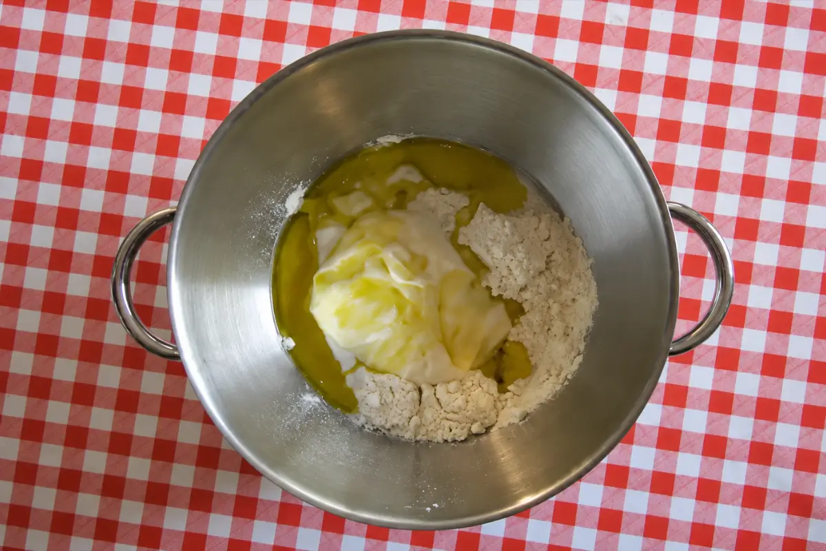 Sourdough Grissini ingredients in the bowl of an electric mixer fitted with a dough hook.