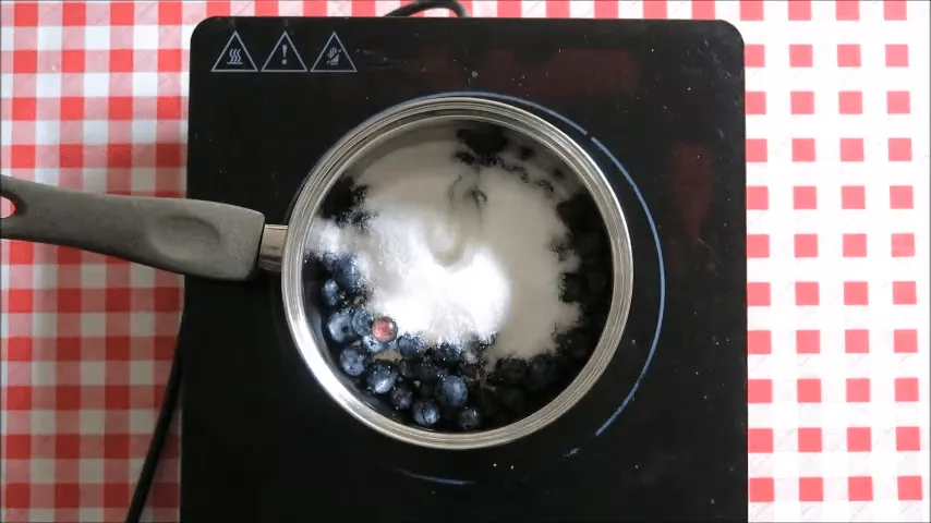 Blueberries mixed with sugar and lemon juice in a saucepan to start homemade blueberry jam.