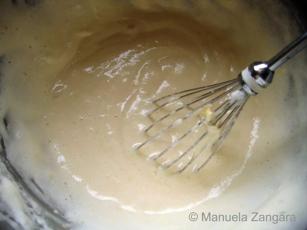 Mixing the sponge cake batter with a whisk until smooth and airy.