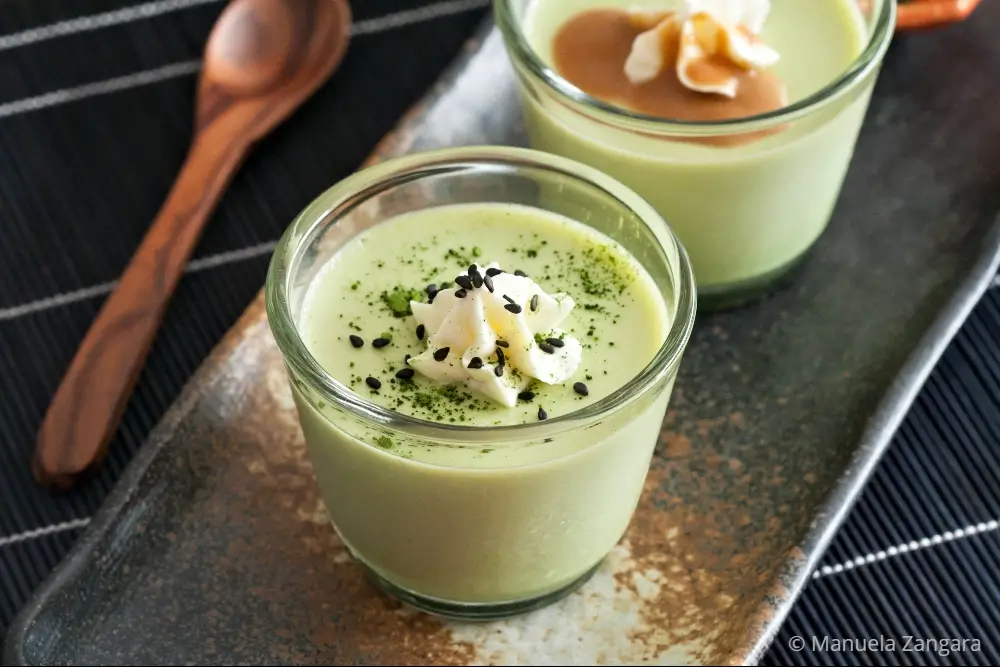 Matcha panna cotta decorated with whipped cream, black sesame seeds, and a dusting of matcha.