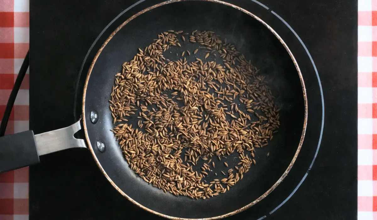 Cumin seeds toasting in a dry pan over medium heat.