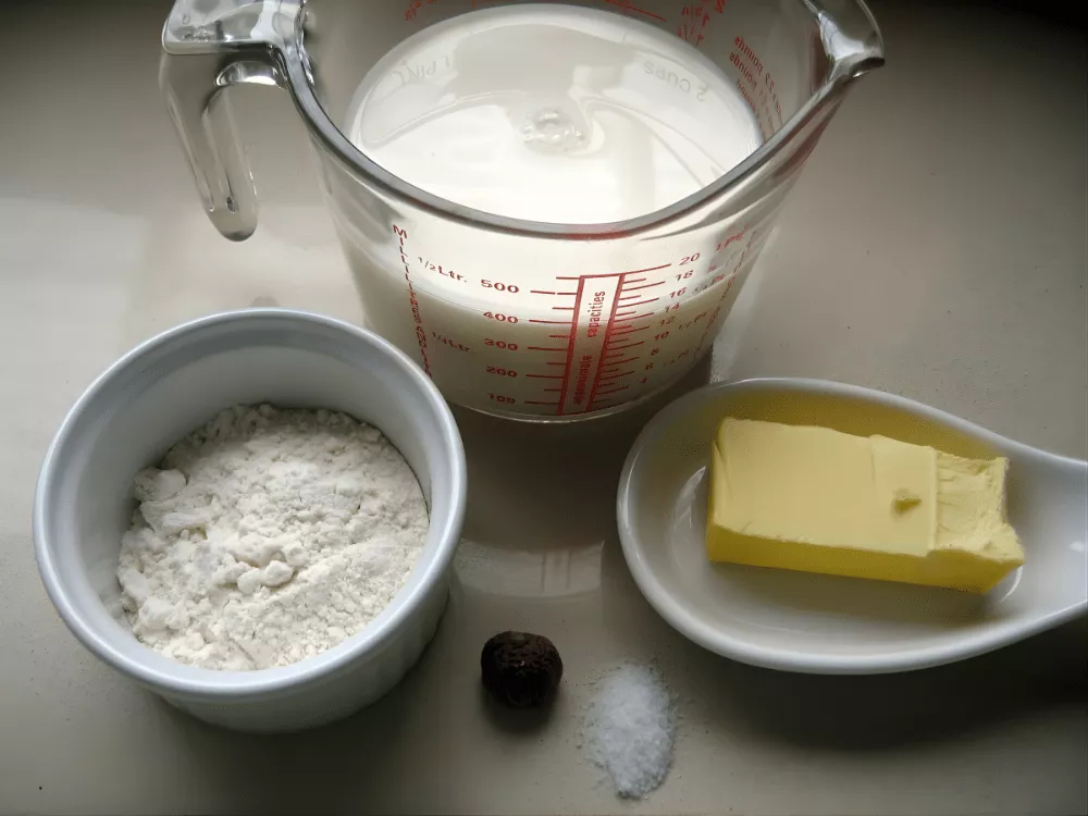 Ingredients for making béchamel sauce arranged on a kitchen counter.