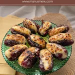 Caramelised stuffed dates with golden tops served on a decorative green glass plate.