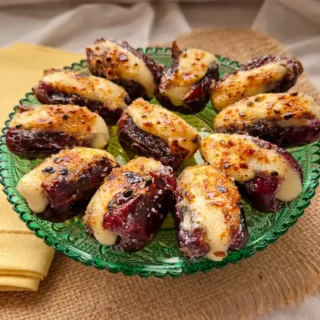 Brie stuffed dates with caramelised sugar topping served on a green plate.