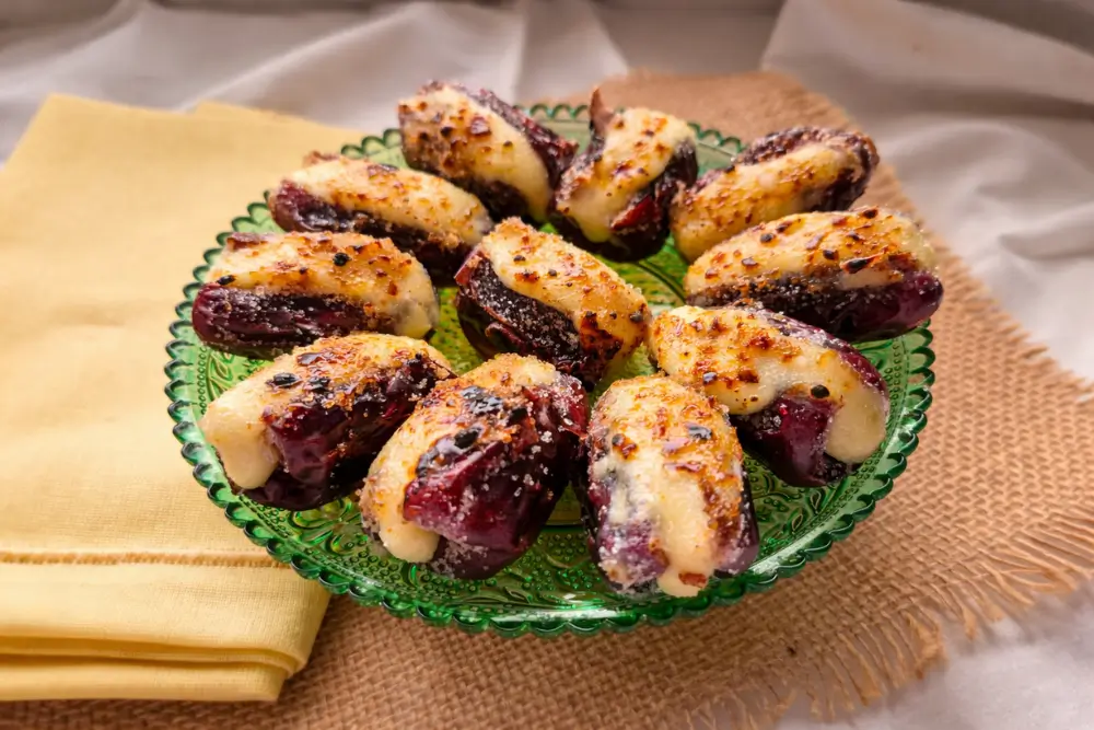 Dates with caramelised sugar topping and creamy cheese filling arranged on a green glass plate.