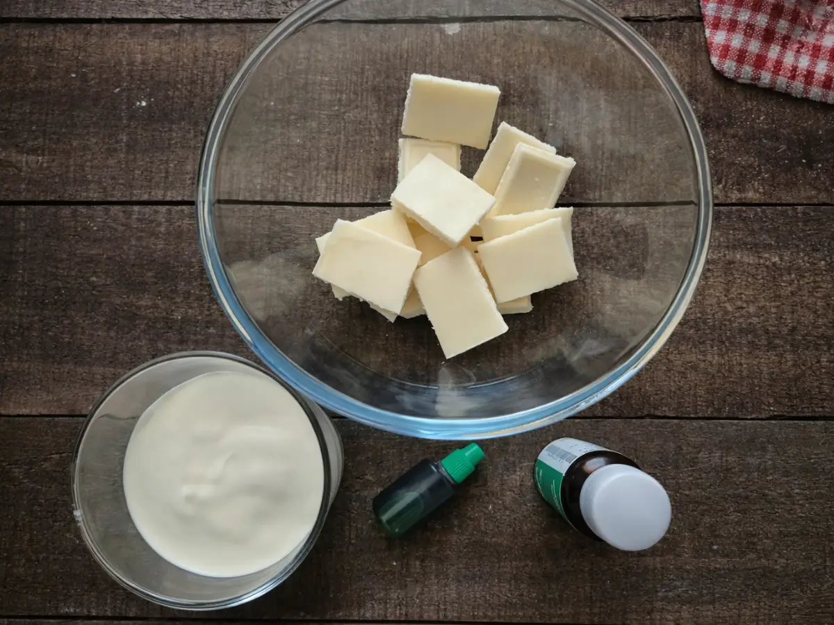 White chocolate pieces, cream, peppermint extract and green colouring arranged in bowls.