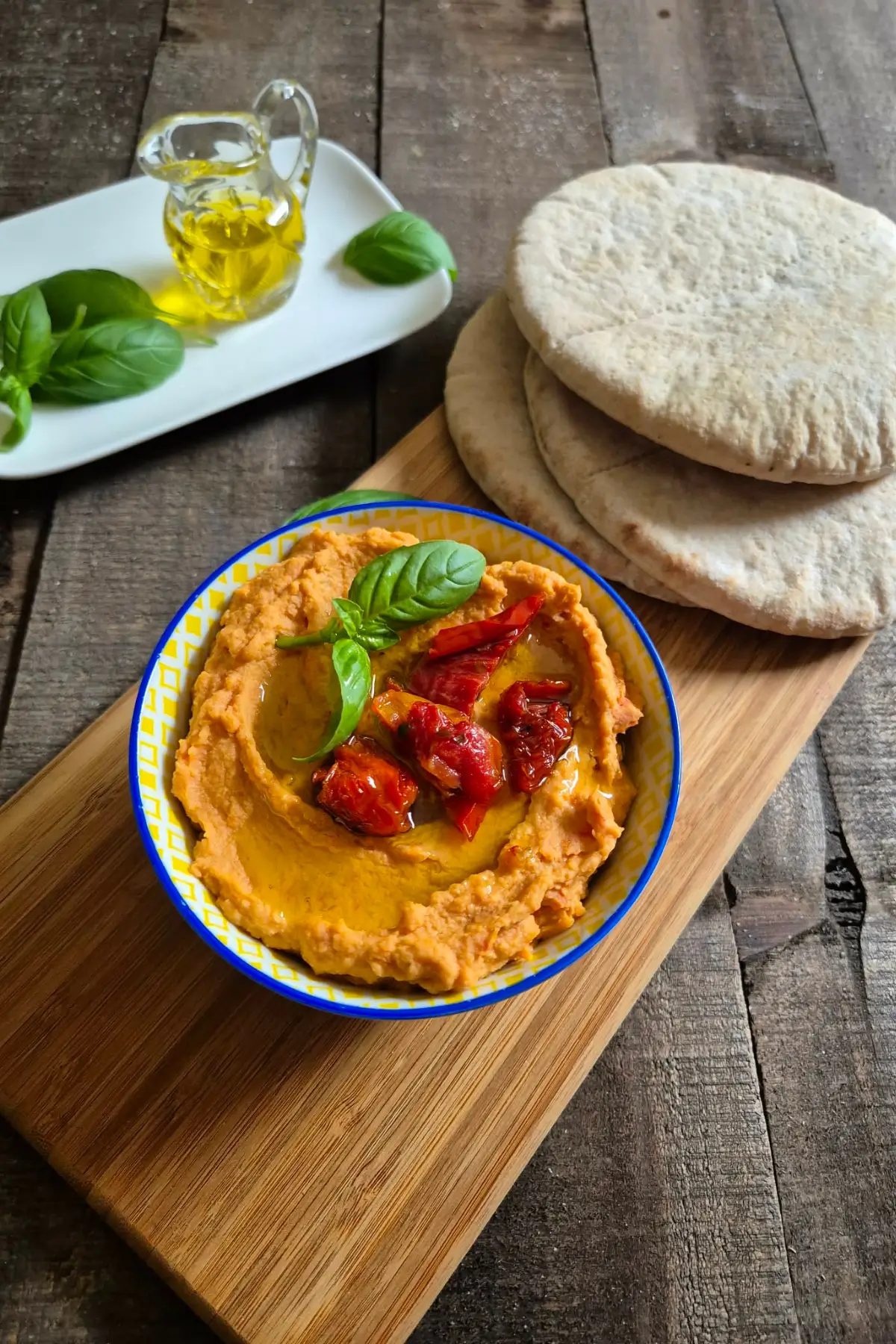 Smooth hummus topped with basil and tomatoes served with warm pita bread.