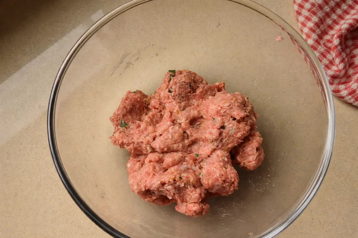 Lamb meatball mixture with mint in a bowl after combining the ingredients.