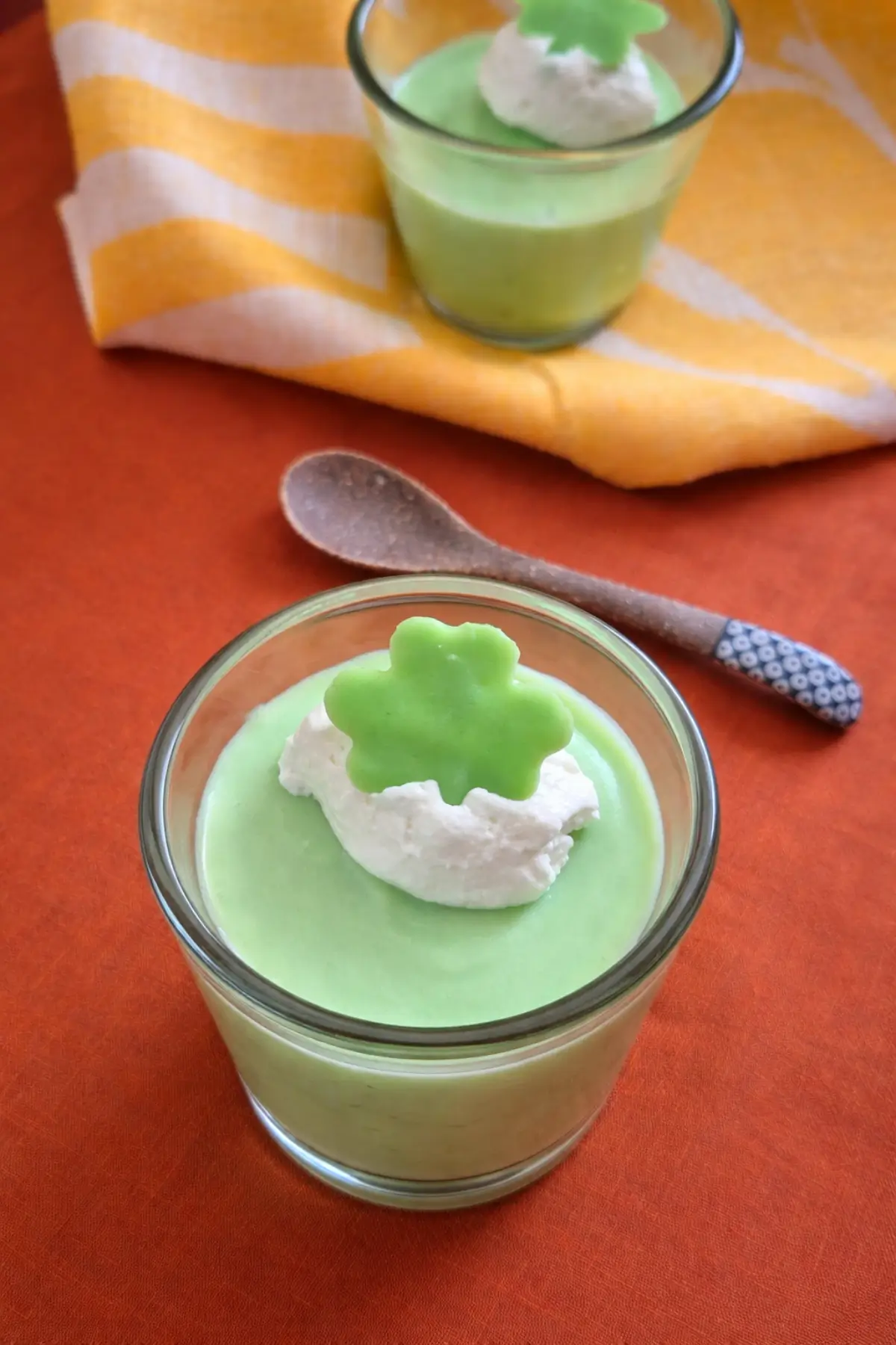 Small glass of green mint dessert with cream and shamrock on top.
