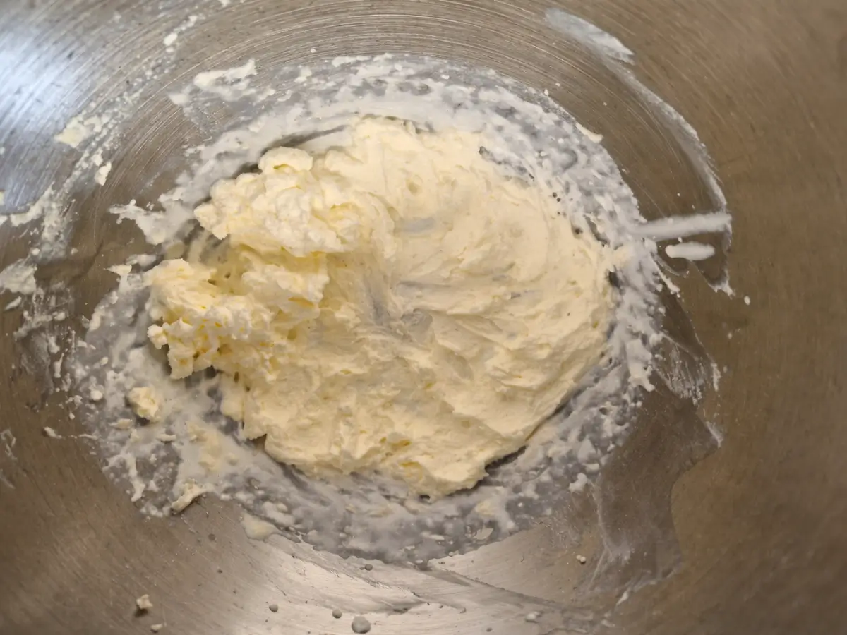 Whipped heavy cream at soft peaks in stainless steel mixing bowl.