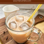 Homemade chai latte served cold with ice on a wooden board with spices.