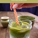 Hand stirring the matcha and milk together in a glass with ice.