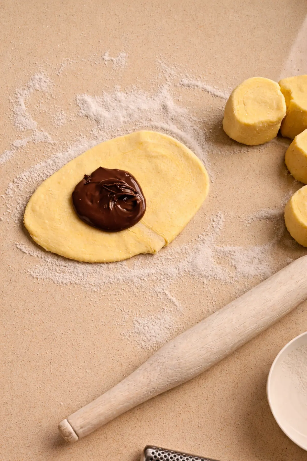 Adding a spoonful of chocolate spread to the centre of the rolled pastry.