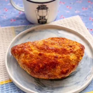 Golden baked Ciavattoni Romani pastry on a plate with crisp sugar-coated surface.