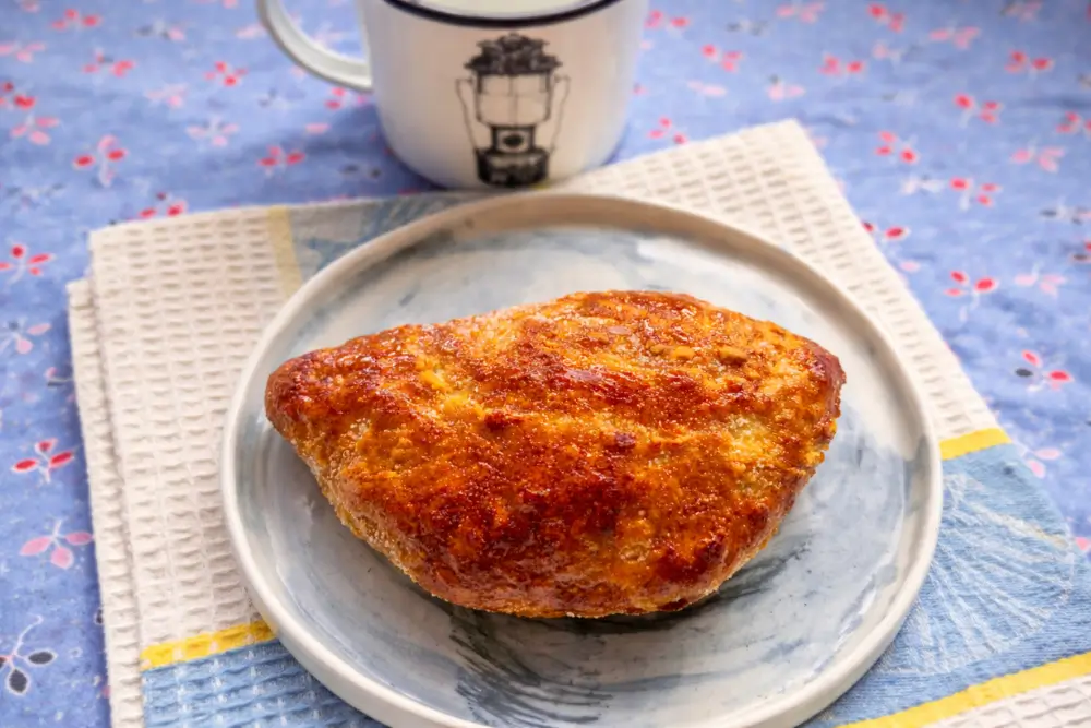 Golden baked Ciavattoni Romani pastry on a plate with crisp sugar-coated surface.