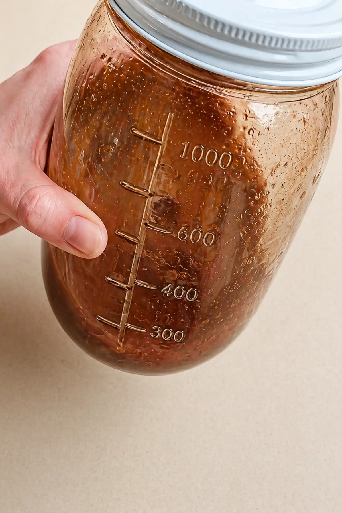 Jar of chai tea concentrate being shaken to combine tea and ground spices.