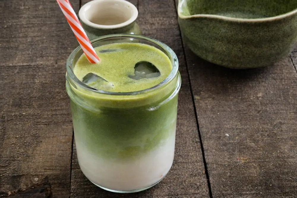 Glass of Iced Matcha Latte with layered milk and matcha over ice.