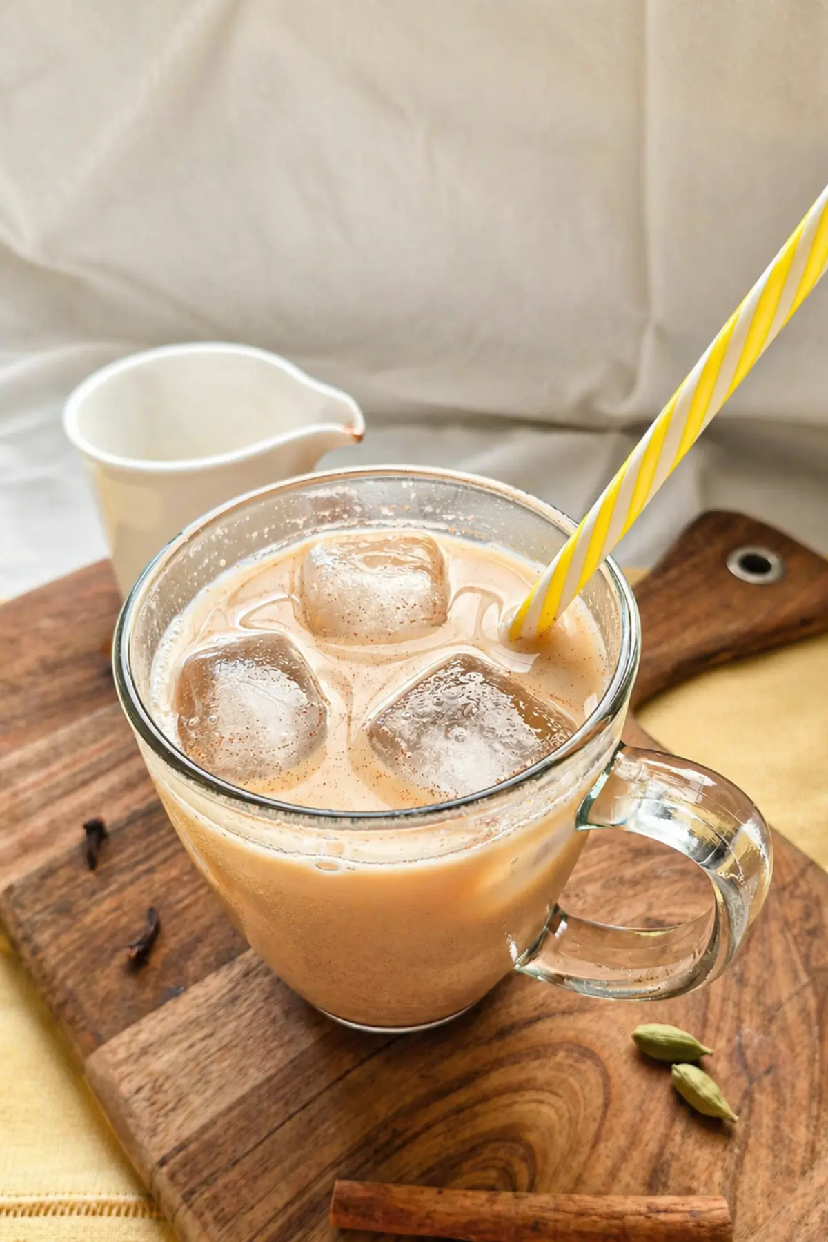 Close-up of an iced tea latte with ice and a striped straw in a glass.