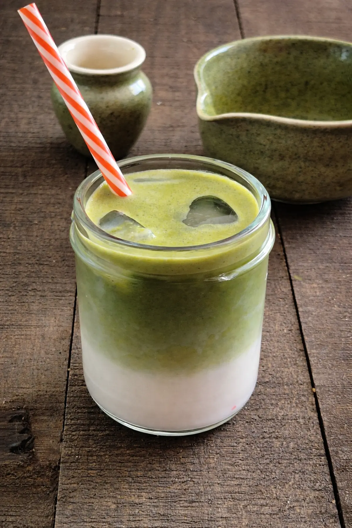 Close-up of a chilled matcha drink with milk and green tea layers in a glass jar.