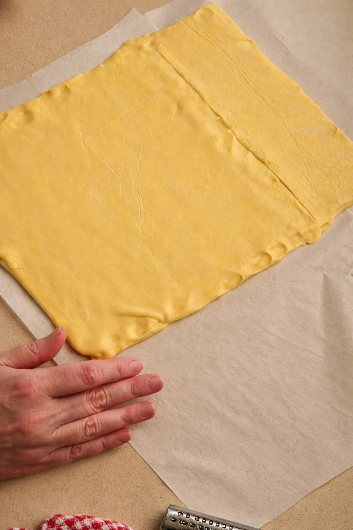 Three puff pastry sheets stacked and pressed together on baking paper.