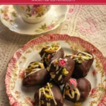 Pistachio chocolate dates decorated with white chocolate drizzle and sugar flowers on a floral plate.