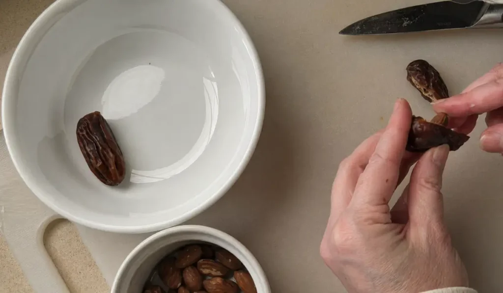 Pressing almonds into split dates before shaping the hearts.