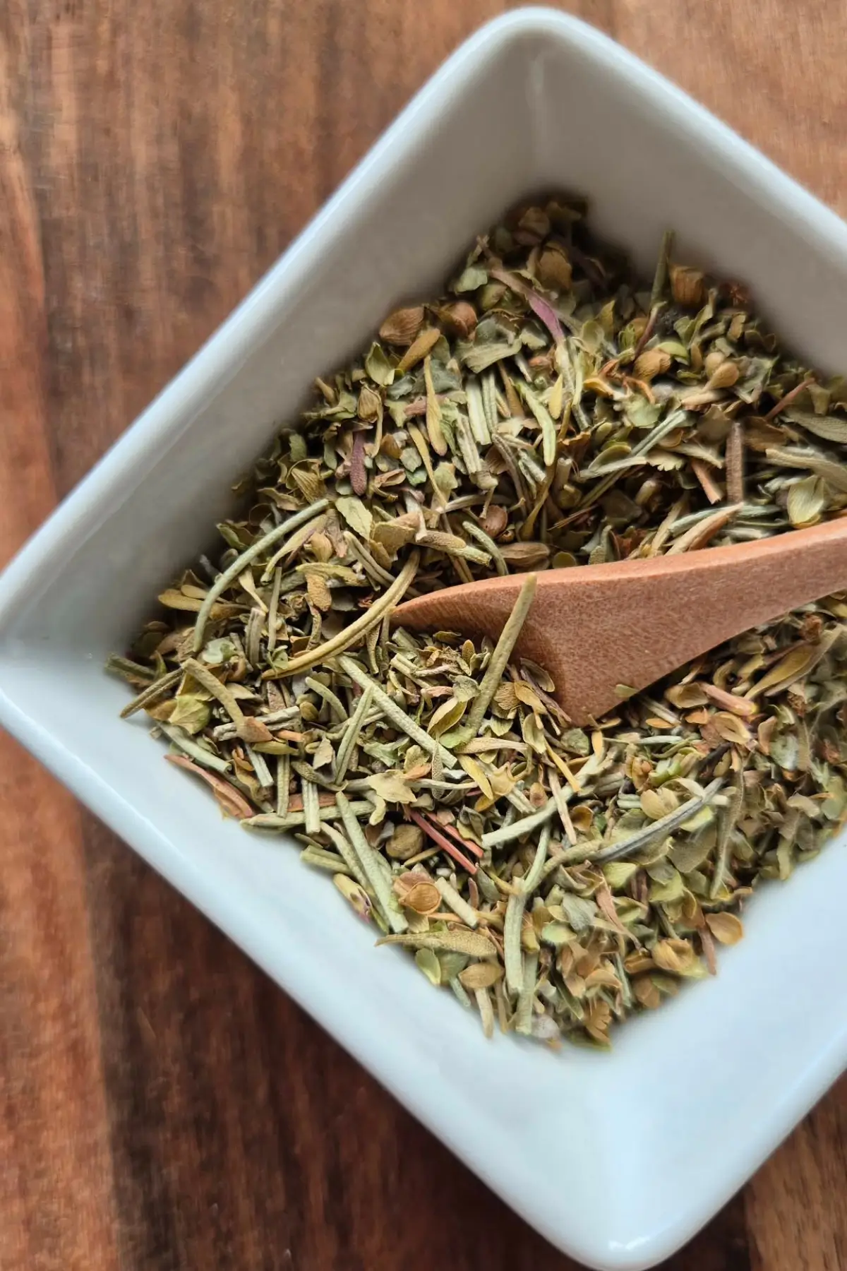 Close-up of a dried herb blend showing rosemary, oregano, thyme, and marjoram.