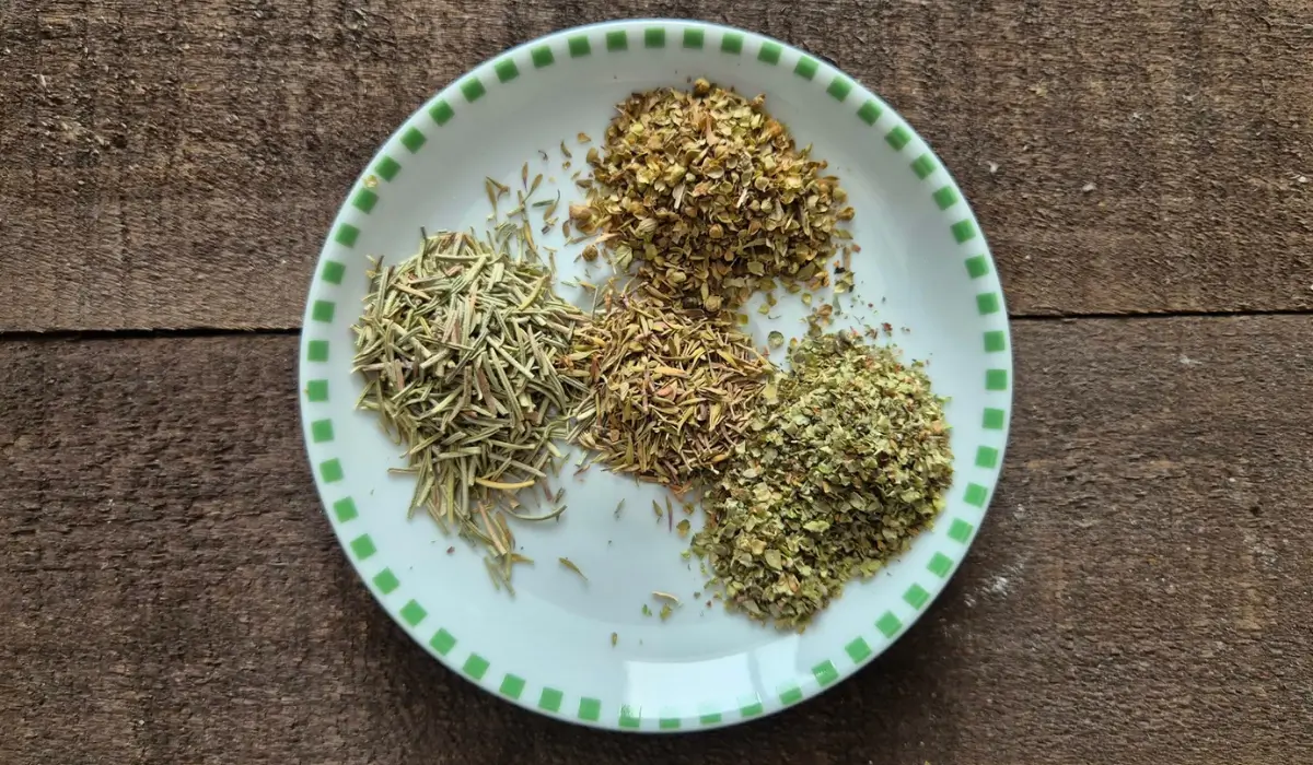 Measured dried herbs arranged separately on a plate before mixing.