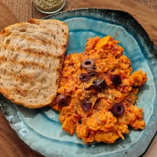 Scrambled Eggs with Tomato served with sliced black olives, Herbes de Provence, and toasted sourdough bread.